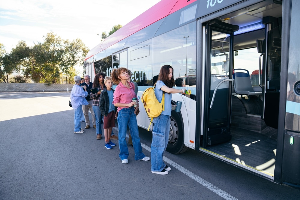 Bus 100% électrique : passagers et transport durable Passagers de tous âges faisant la queue pour monter dans un bus 100% électrique moderne et écologique.