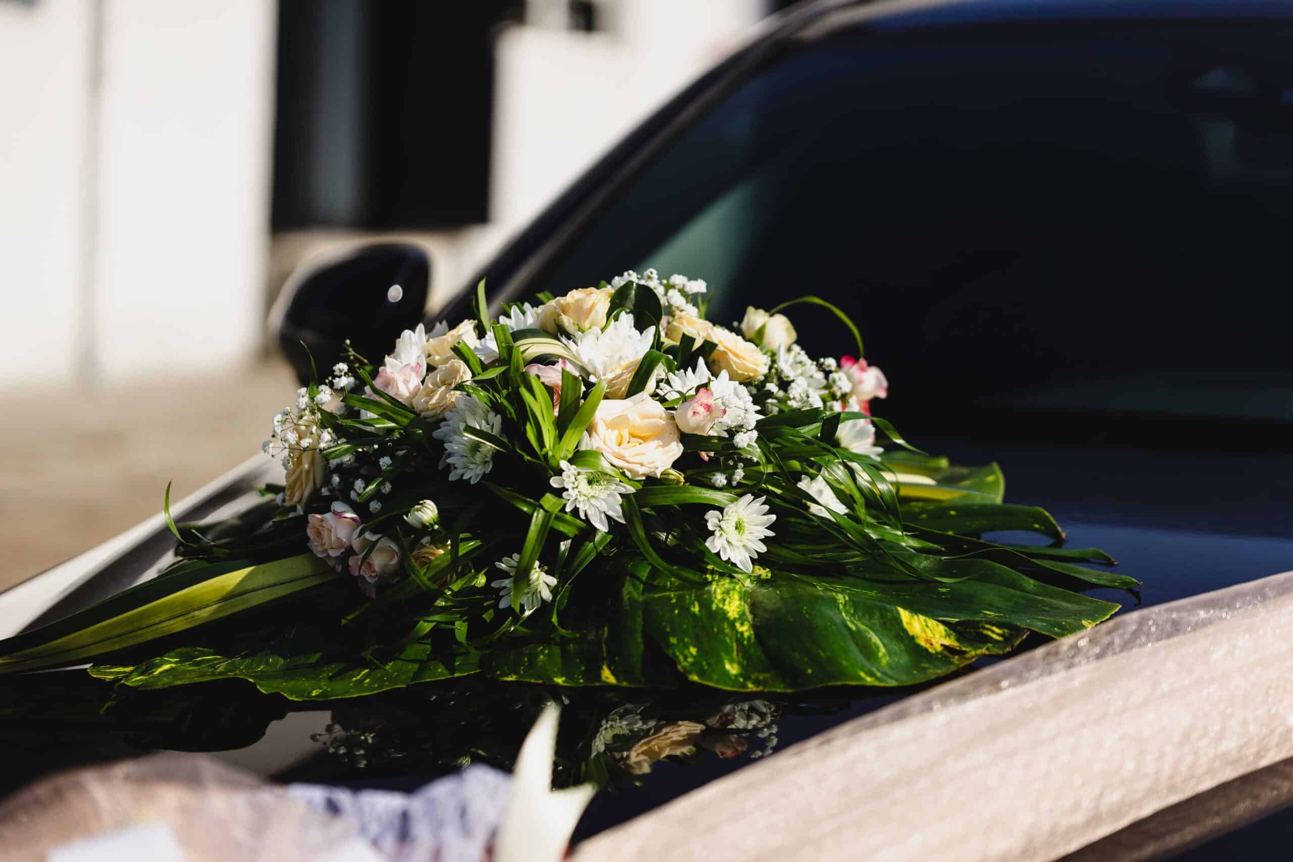 Beautiful floral arrangement on a wedding car, featuring white and pink flowers with greenery, perfect for a wedding day.
